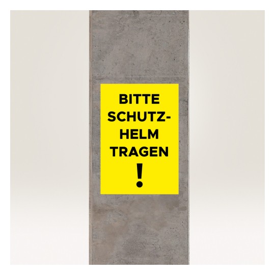 Изображение показывает желтый знак на бетонной колонне с надписью 'BITTE SCHUTZ-HELM TRAGEN!', что переводится как 'Пожалуйста, надевайте шлем!' указывая на требование безопасности.