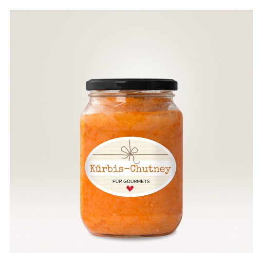 Изображение показывает банку с Kürbis-Chutney с декоративной этикеткой. Чатни имеет ярко-оранжевый цвет, а крышка банки черная. На этикетке на светлом фоне размещен текст 'Kürbis-Chutney für Gourmets'.