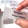 Изображение показывает руку, держащую карточку с надписями «Avery» и «Paul Meyer», указывающими, что ее легко отделить и у нее гладкие края. На заднем плане видно множество карточек.
