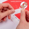Изображение, на котором руки сдирают пломбу с устойчивым к вскрытию покрытием с красной поверхности. На лейбле изображён узор, а вверху написано "УСТОЙЧИВО К ВСКРЫТИЮ". Вставка крупным планом показывает использование лейбла на запястье.