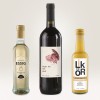 Изображение содержит три бутылки: бутылка яблочного бальзамического уксуса, бутылка красного вина с этикеткой «Night Owl» и бутылка кремового ликера. Они расположены на светлом фоне.