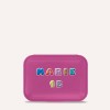 Изображение показывает розовый прямоугольный футляр с именем "MARIE" и надписью "1B", выполненной разноцветными буквами.